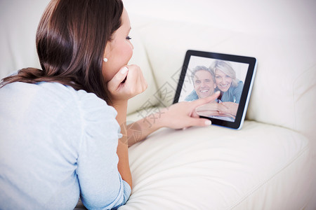 情侣在镜头前微笑的复合图像沙发住所亲密感感情视频家庭棕色触摸屏闲暇金发背景图片