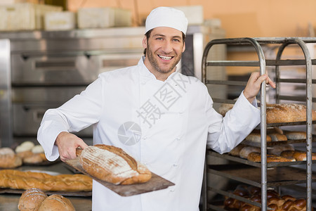 微笑面包师看着拿着面包的照相机背景图片