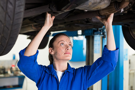 汽车下面的机械检查女性服务车辆女士作坊机械师工作服工人车库工程师背景图片