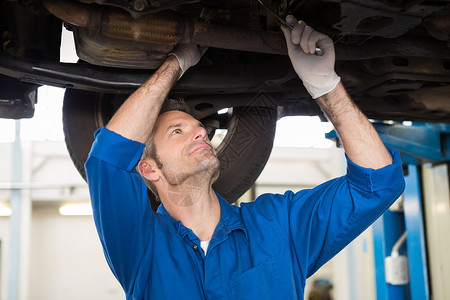 汽车下面的机械检查车库修复作坊蓝色手套男人修理工作服服务扳手背景图片