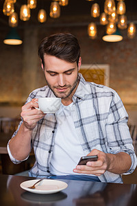 年轻人喝咖啡的年轻男人杯子男性顾客餐厅咖啡馆技术手机电话咖啡屋食品背景图片