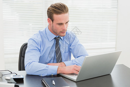 利用笔记本电脑集中经营的商务人士桌子计算器眼镜旋转椅领带男人专注职场办公室人士背景图片
