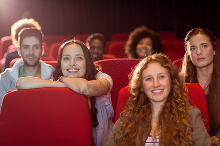 年轻朋友看电影椅子闲暇黑色电影院友谊电影业时间电影微笑女士背景图片