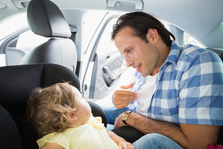 保护车辆安全父亲在汽车座椅上保护他的孩子紧固件旅行运输后座闲暇家庭团结婴儿男人快乐背景
