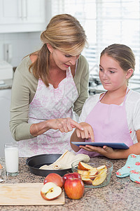 幸福的母亲和女儿一起做蛋糕的快乐母亲和女儿家庭台面家庭生活食谱孩子平板药片住所女孩烘烤背景图片