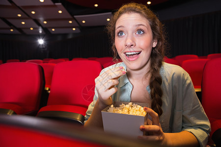 年轻女性看电影演出椅子娱乐文艺快乐电影礼堂活动电影院红色背景图片