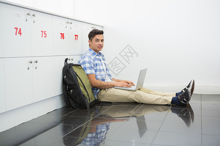带着笔记本电脑坐在地上微笑的大学生背景图片