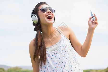 漂亮的黑发 听音乐公园绿色听力闲暇音乐太阳镜潮人微笑农村绿地背景图片