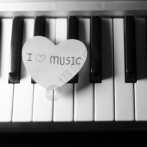 黑白钢琴键盘上的纸心娱乐乐器工作室艺术钥匙音乐笔记宏观旋律合成器背景图片