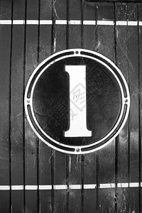 登顶标志数字一 旧式标志 在圆形金属和油漆上 用黑色和白色的变换风格图像挂在木制面板墙上背景