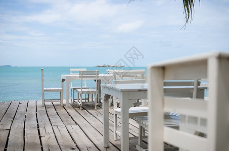 萨米特白椅子和白桌天空风景休息热带场景休息室海洋躺椅木头海岸线背景