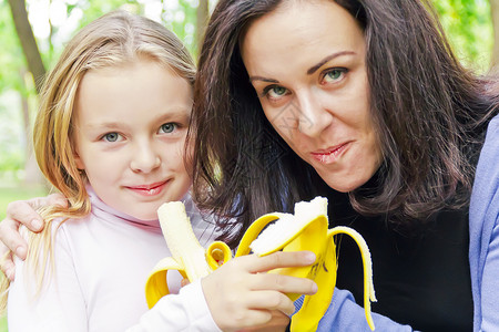 母亲和女儿吃香蕉女士孩子女性童年白色女学生父母家庭背景图片