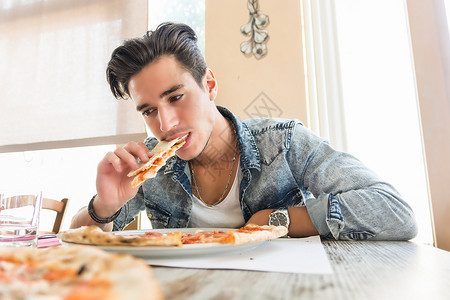 英俊的年轻人在家里吃披萨背景图片
