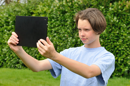 女孩使用数字平板电脑笔记本工作药片互联网自拍花园数位板照片女性闲暇背景图片