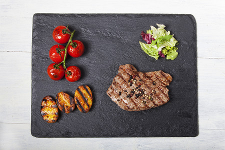一块板板盘上多汁的牛排沙拉盘子蔬菜黑色土豆牛肉辣椒香料食物炙烤背景图片