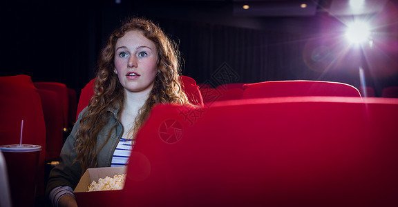 年轻女性看电影娱乐红色座位电影玻璃杯电影业礼堂活动爆米花电影院背景图片