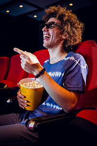 年轻人在看一部3D电影活动时间演出电影业男性男人座位文艺微笑爆米花背景图片