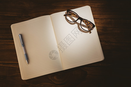带阅读眼镜的空白笔记纸记事本木头桌子阴影教育商业页数背景图片