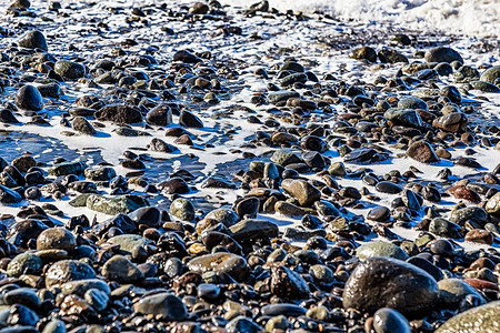 海滩上有泡沫的石头背景图片