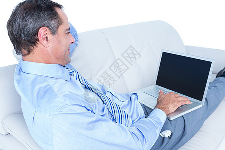 躺在沙发上拿着笔记本电脑的笑脸商务人士人士快乐网站男性技术互联网购物闲暇商务微笑背景图片