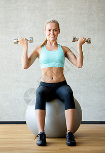 带着哑铃和练球的笑着女人力量快乐身体幸福肌肉运动装损失灵活性训练重量背景图片