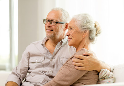 在家沙发上坐着幸福的老年情侣丈夫快乐闲暇妻子长椅祖父母退休拥抱房间家庭背景图片