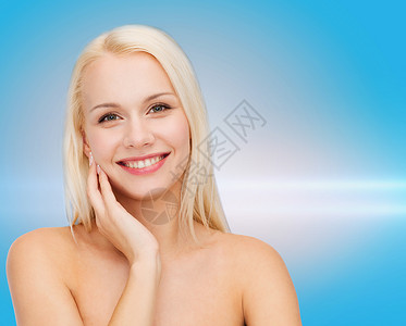 微笑的年轻女子触摸她的面皮护理容貌女性金发女郎蓝色福利皮肤激光清洁女孩背景图片