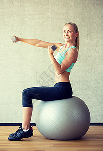 带着哑铃和练球的笑着女人快乐健身身体有氧运动平衡微笑运动装二头肌重量训练背景图片