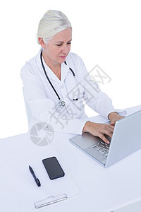 在笔记本电脑上工作的医生实验工作服专注医疗女性服务从业者桌子技术专家背景图片