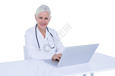 在笔记本电脑上工作的医生技术专注医疗女性实验工作服桌子从业者专家服务背景图片