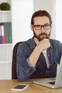 在笔记本电脑上工作的嬉皮士商务人士商业商务男性衬衫职业潮人办公室机构牛仔男人背景图片