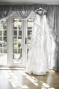 白婚服挂在有太阳的窗帘杆上背景图片