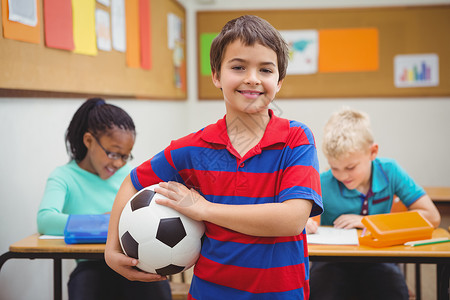 手持足球的微笑学生教育学校童年桌子黑色男生小学班级女性快乐背景图片