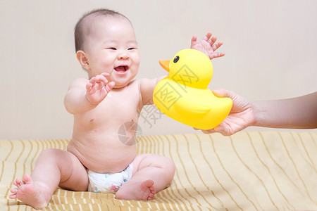 亚洲泰国女婴玩黄橡皮鸭的亚洲泰籍女婴微笑黄色女孩儿童喜悦女儿孩子尿布白色鸭子背景图片