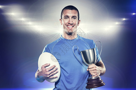 拥有奖杯和球的微笑橄榄球运动员画像综合图象运动竞赛聚光灯快乐欣快感体育胜利金属反射裁剪背景图片