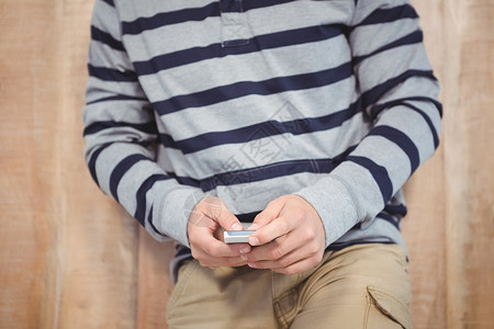 使用智能手机的中层人沟通休闲潮人闲暇棕色男性倾斜短信木头服装背景图片