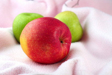 粉色布上红苹果和绿苹果背景图片
