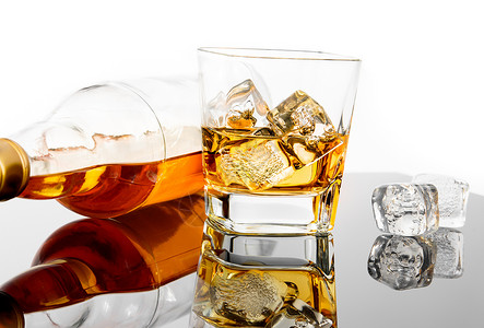 玻璃威士忌 靠近瓶子和冰块 在黑桌面上与反光背景图片