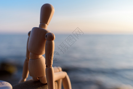 傻子坐在石头上玩具韧性塑像雕塑海滩海洋卡通片姿势人体模型背景图片