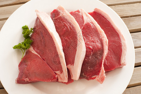 盘子上四块新鲜牛肉牛排背景图片