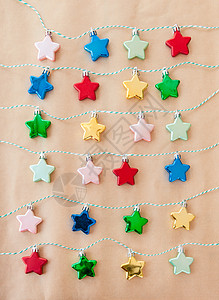 棕纸上多彩星星红色小玩意儿缠绕粉色花环日历绿色蓝色星形背景图片
