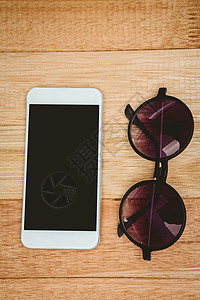 眼镜和智能手机视图木头屏幕触摸屏时尚电话技术太阳镜桌子白色背景图片