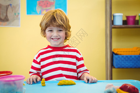 制作泥土模型的快乐男孩娱乐性创造力艺术类乐趣艺术黏土工艺头发微笑桌子背景图片