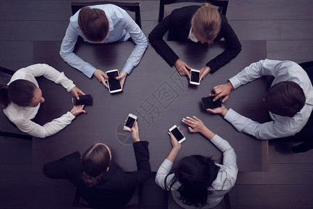拥有智能手机的商务人士团队团体会议公司桌子互联网办公室技术商务电话背景图片