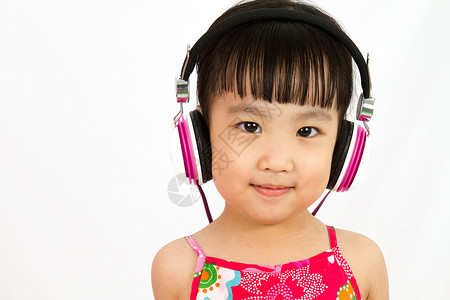 使用耳机的中国小女孩享受孩子白色闲暇音乐女孩快乐喜悦娱乐韵律背景图片
