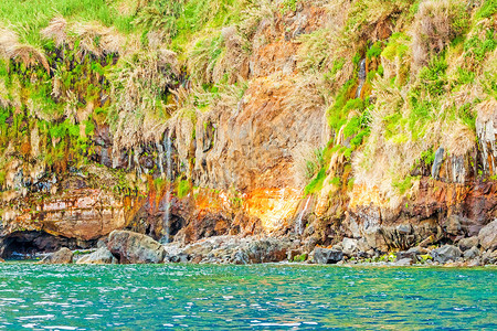 马德拉群岛马德拉的多彩岩石悬崖海岸摇滚海岸线岩壁火山表面橙子废料海洋热带旅游背景