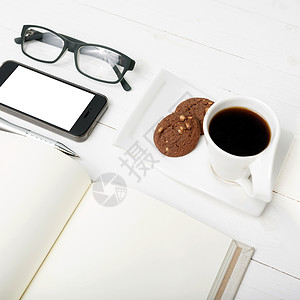 装有饼干 电话 笔记本和眼镜的咖啡杯办公室网络钥匙咖啡细胞杯子工作桌子背景图片