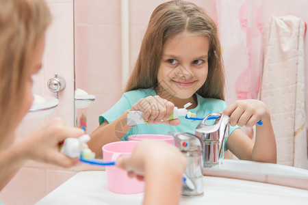 快乐的小女孩挤牙膏 从牙刷上一根管子上的牙膏背景图片
