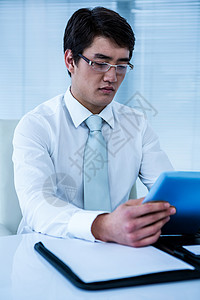 严重的亚洲商务人士使用他的平板电脑夹克商务职业领带职场专注旋转椅男性商业公司背景图片