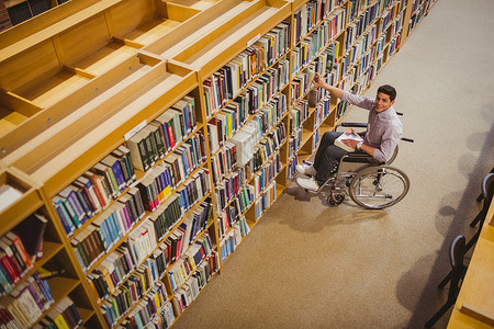 轮椅学生从架子上取书辅助书柜教育残疾人采摘知识图书搜索书架功能背景图片